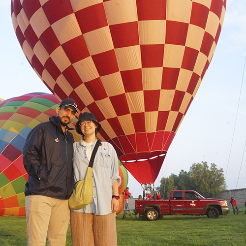 Viajeros junto a globos de colores al amanecer